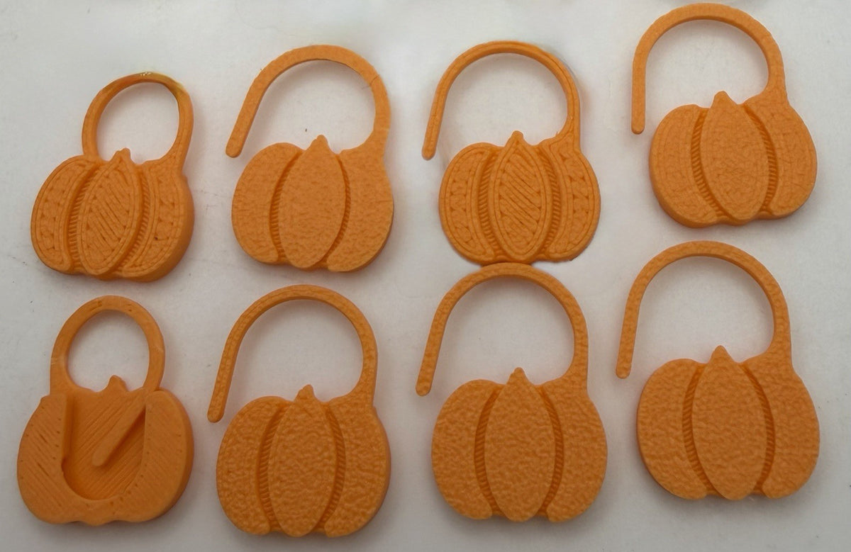Orange pumpkin Halloween stitch markers laid out in rows