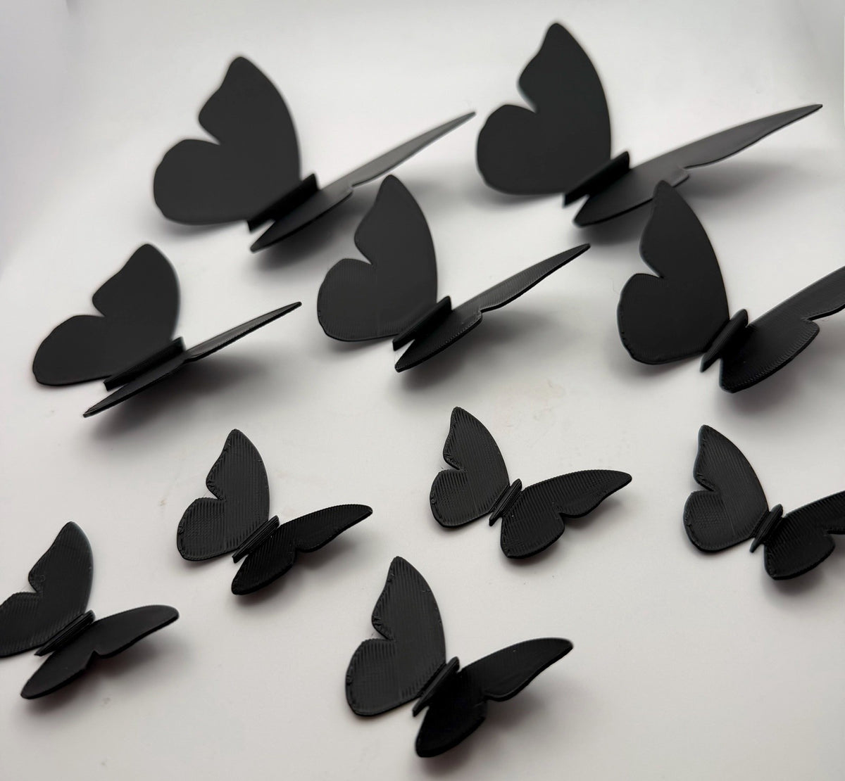 Black 3D printed butterfly wall decorations arranged in a flowing display