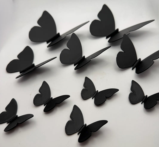 Black 3D printed butterfly wall decorations arranged in a flowing display