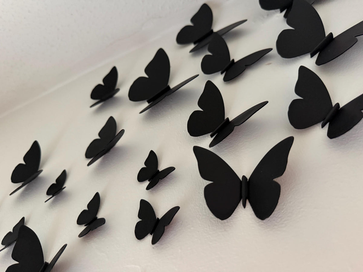 Cluster of black 3D printed butterflies on a light wall