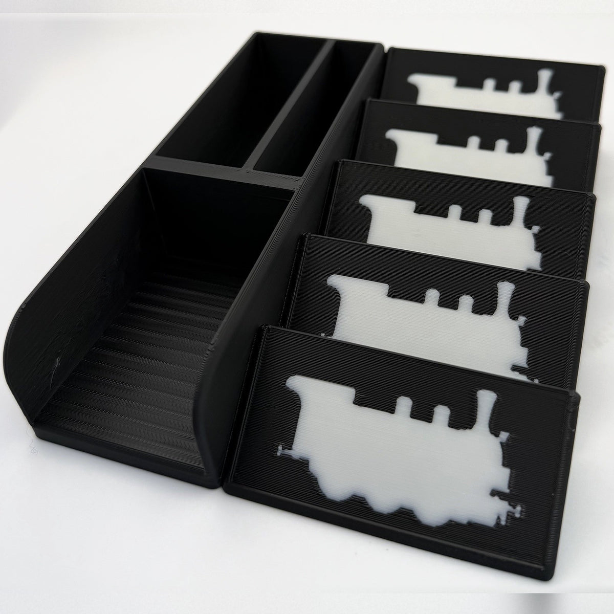 Empty black card organiser from above, white train silhouettes on the display plates - compatible with Ticket to Ride