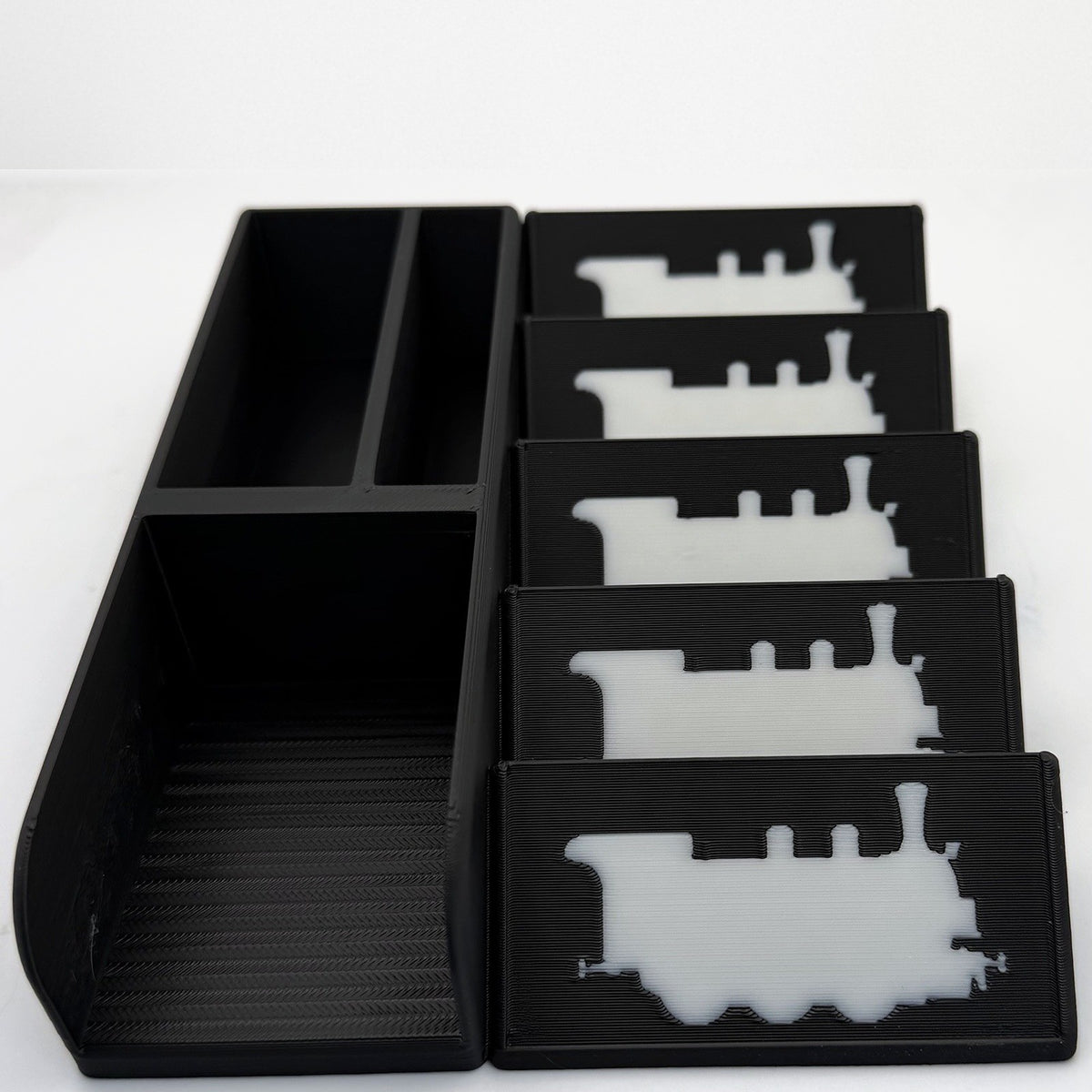 Empty black card organiser from above, white train silhouettes on the display plates - compatible with Ticket to Ride