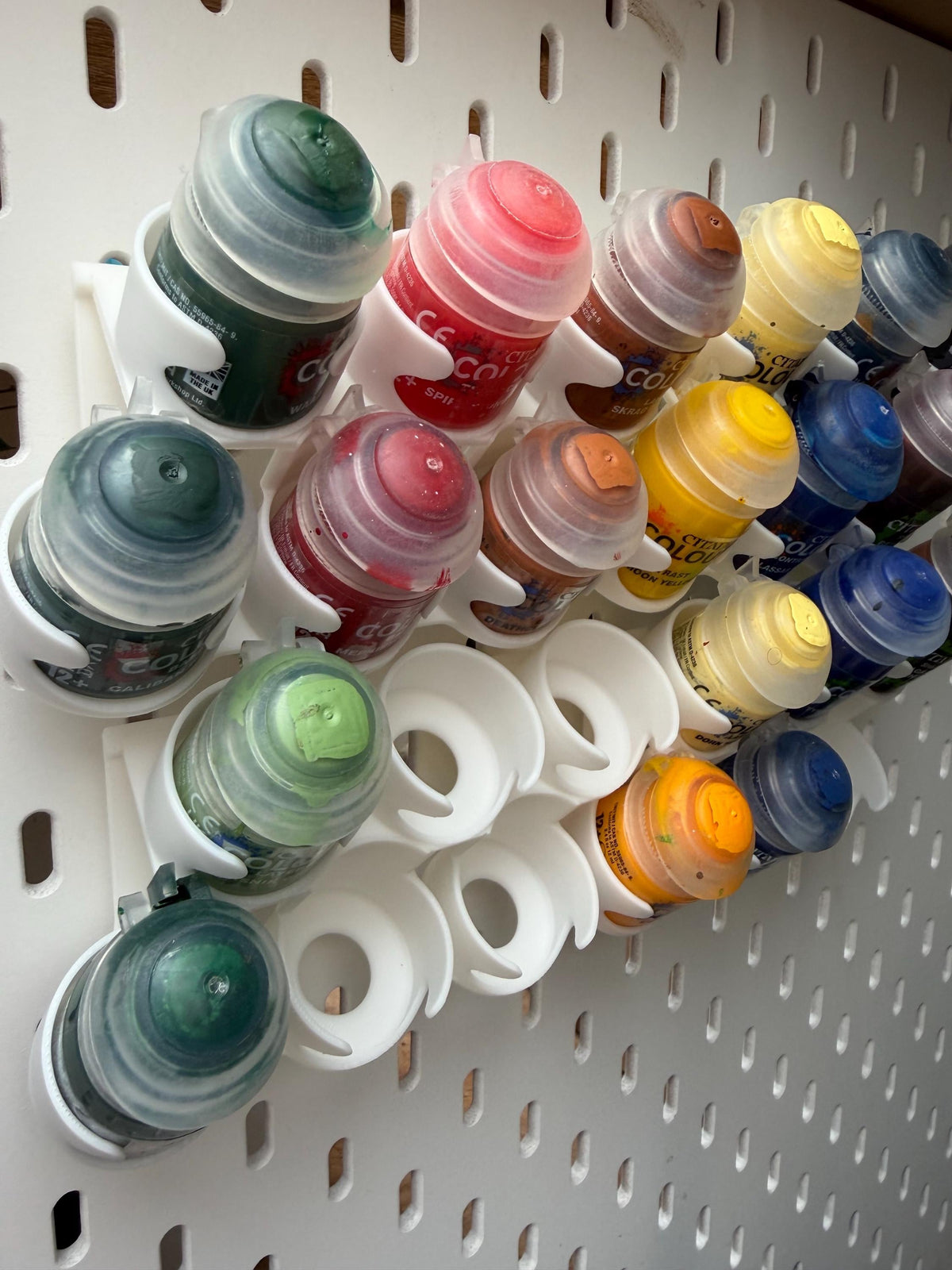 White staggered Citadel paint pot holders for IKEA SKÅDIS pegboard close-up