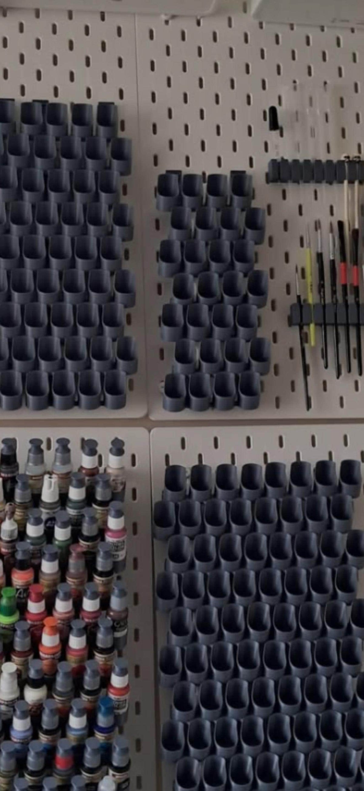 Grey dropper bottle paint holders on IKEA SKÅDIS pegboards showing filled and empty capacities