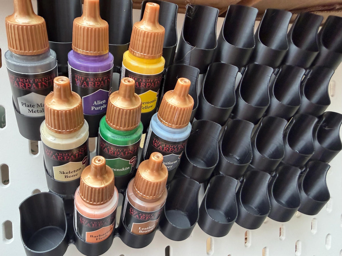 Black dropper bottle paint holders on IKEA SKÅDIS pegboard - close angled view