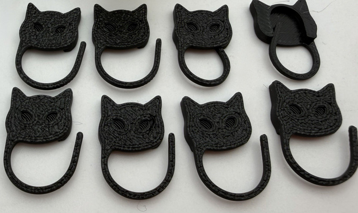 Black cat Halloween stitch markers laid out in rows