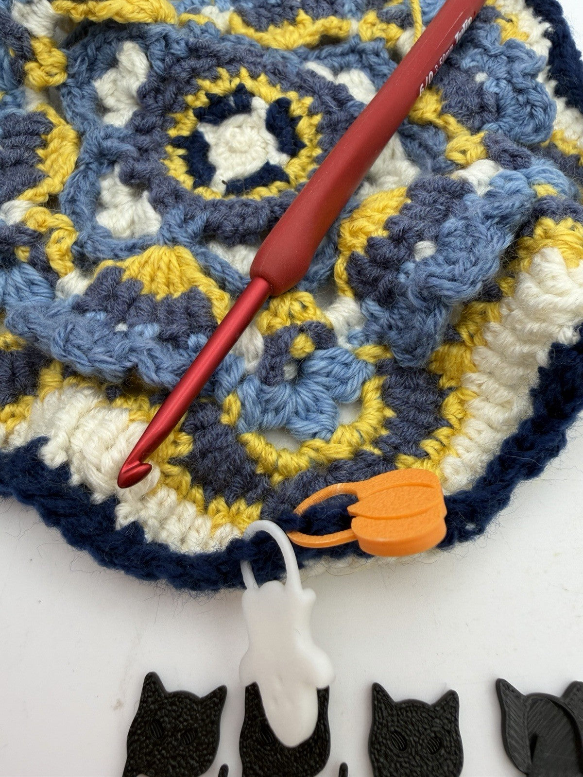 Orange pumpkin stitch marker clipped into a crochet project