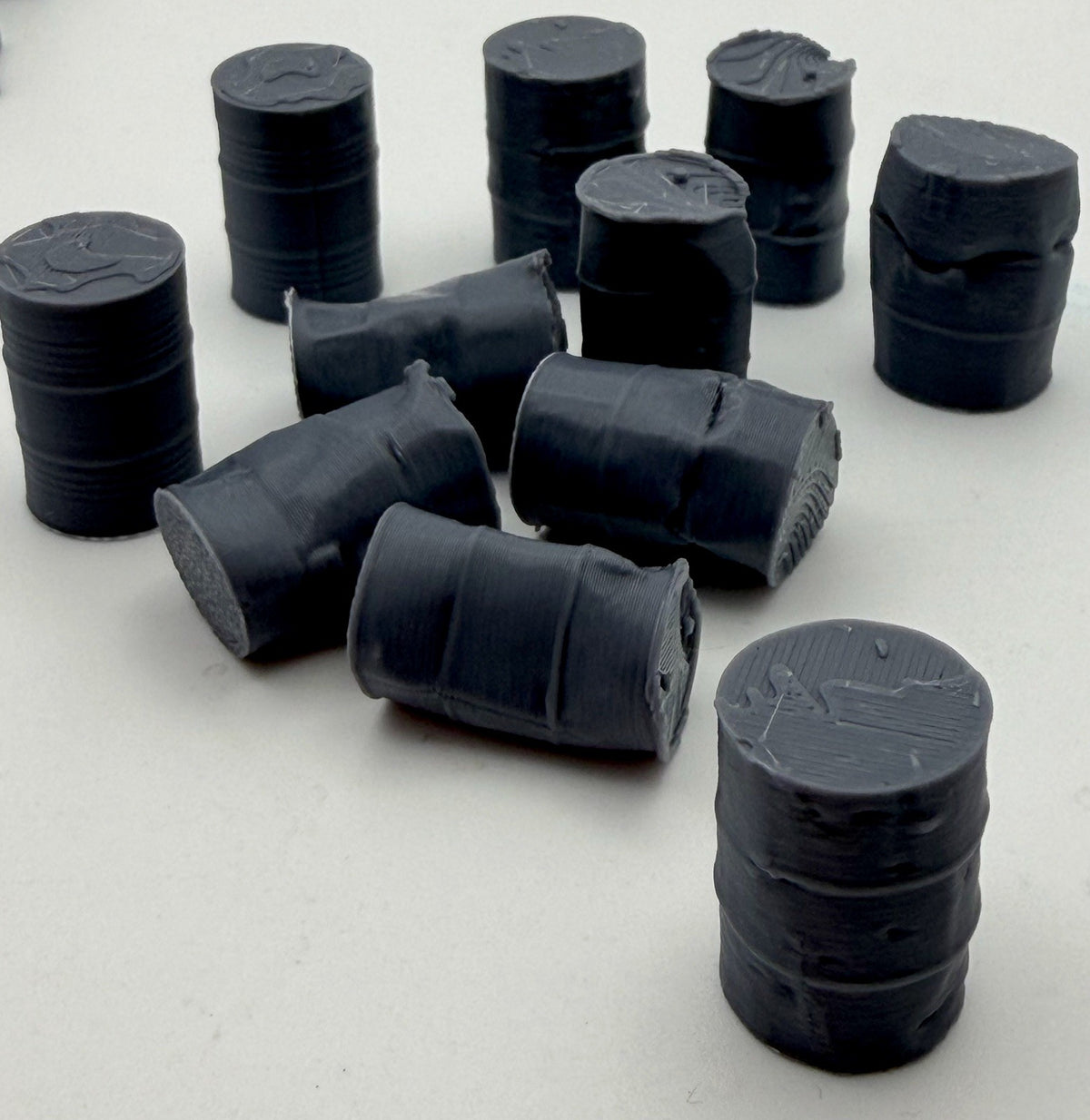 Mixed condition oil drums: upright, fallen and dented drums grouped together