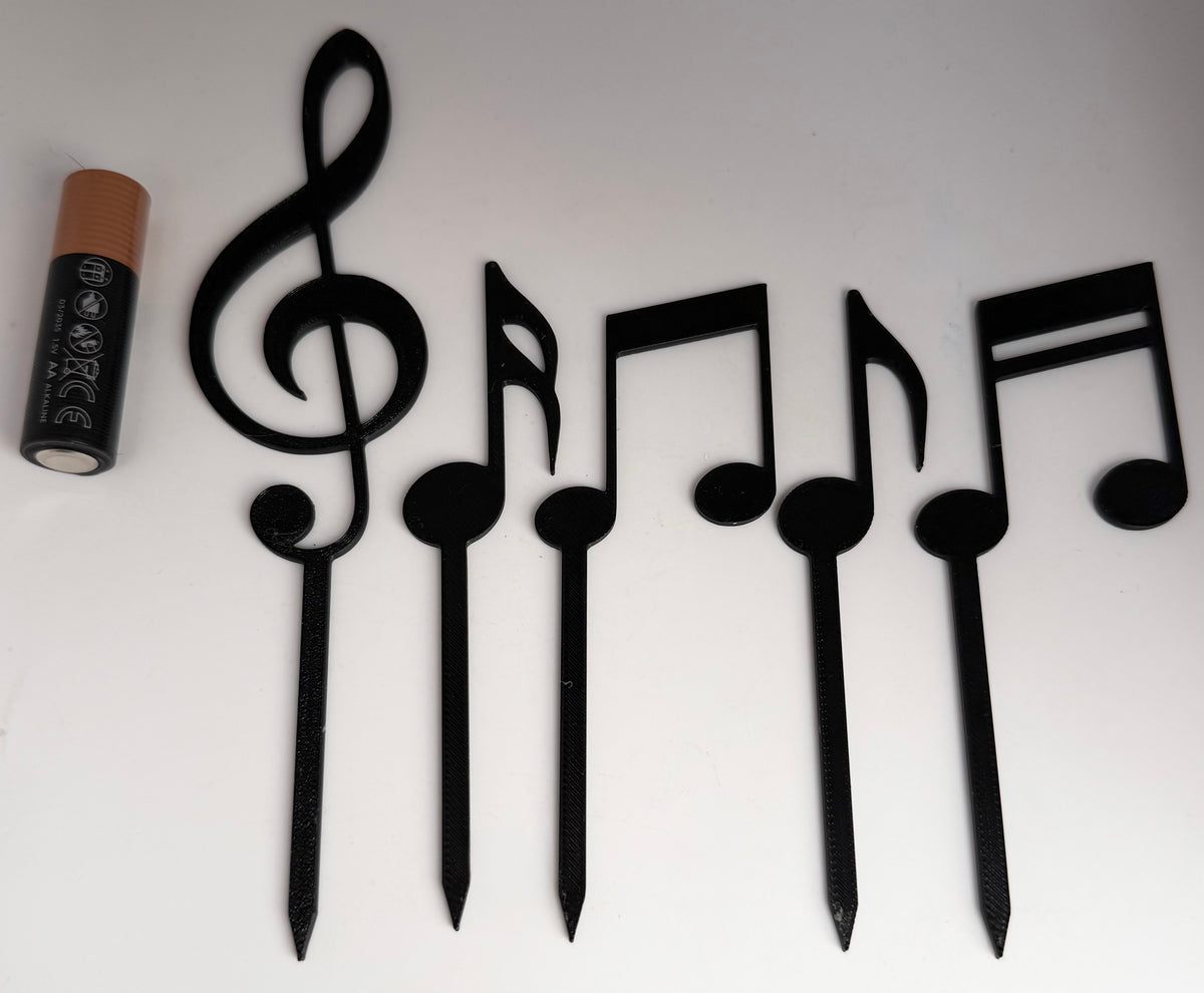 Music note cake toppers next to an AA battery for scale