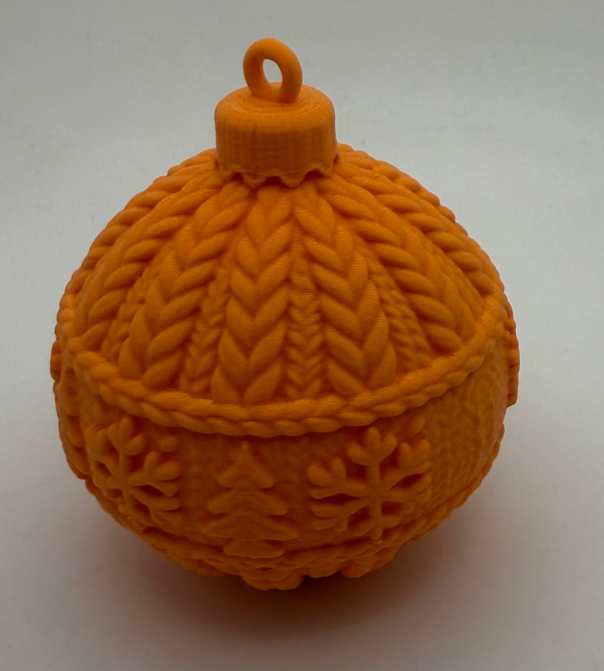 Orange knitted-effect Christmas bauble showing cable-knit and snowflake band