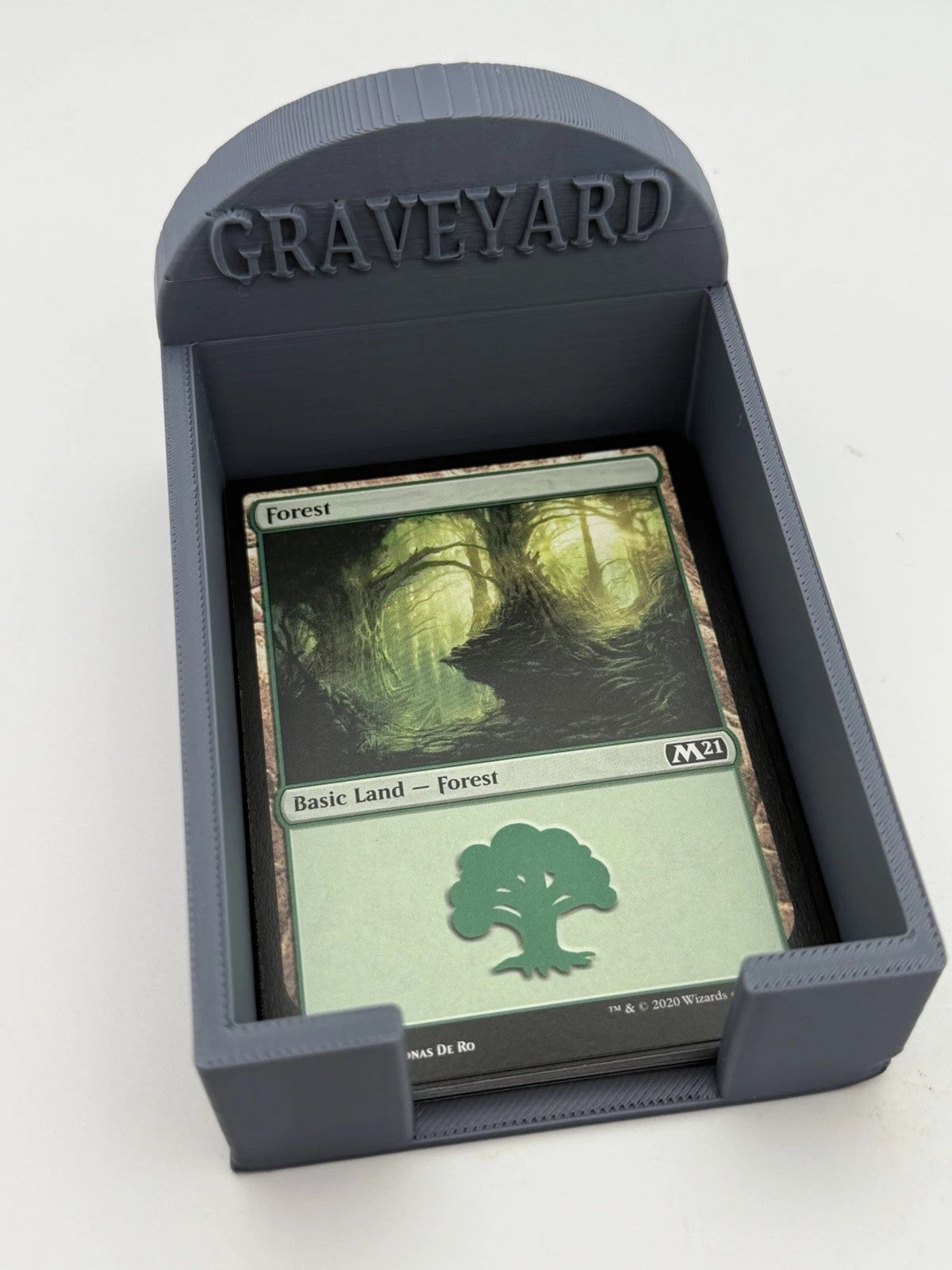 Graveyard card holder shaped like a tombstone holding a pile of Magic: The Gathering cards