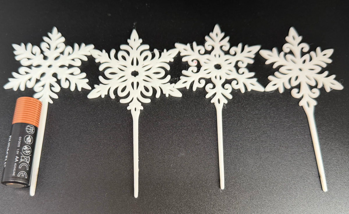 Snowflake cake toppers next to an AA battery for scale