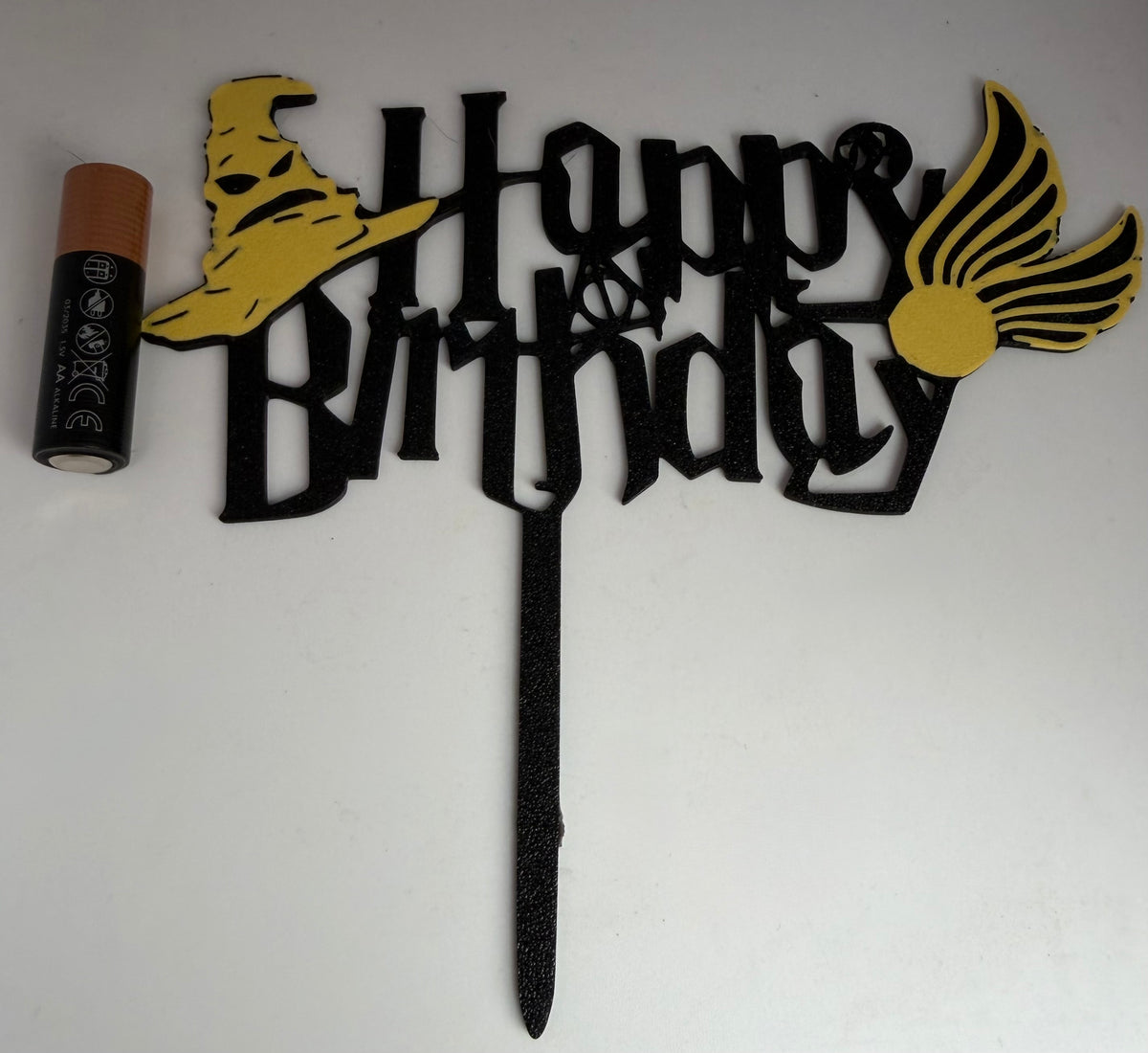 Wizard Happy Birthday cake topper next to an AA battery for scale